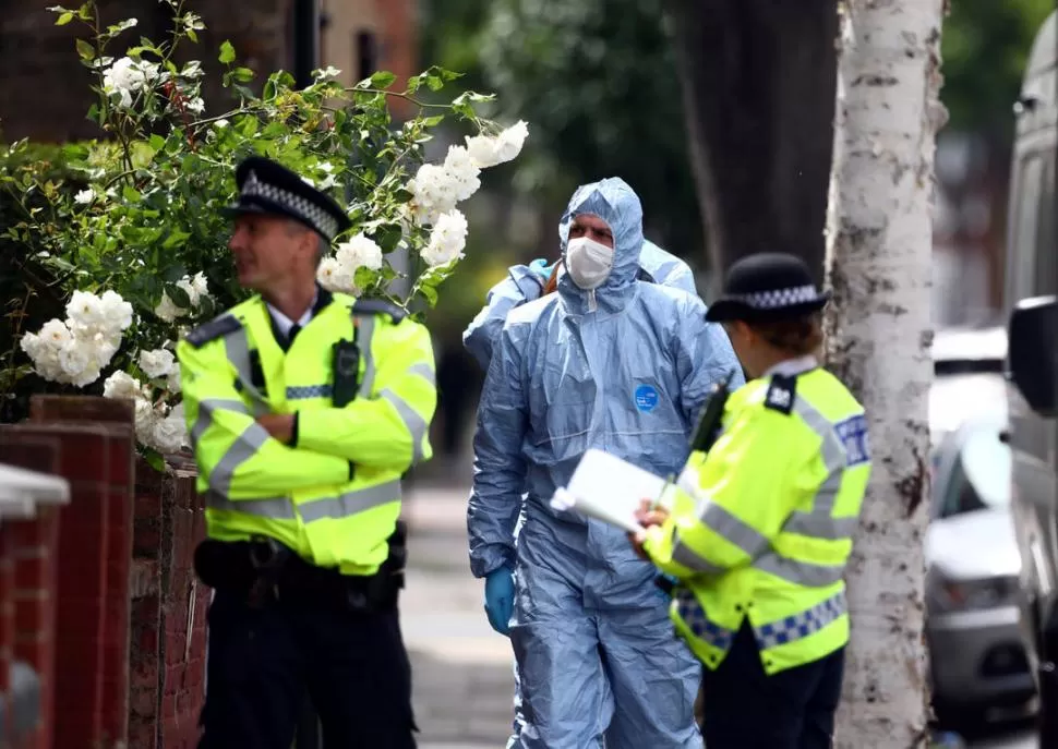 CONTROL Y RECUERDO. Funcionarios policiales siguieron buscando pruebas en uno de los lugares del ataque, donde un londinense depositó flores. Reuters
