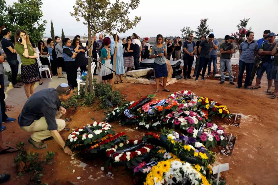 CISJORDANIA OCUPADA. Familiares lloran en las tumbas de Haya, Elad y Yossi, muertos en el ataque del viernes al asentamiento judío de Neve Tsuf. reuters