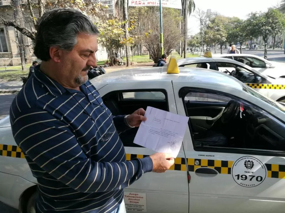 FRENTE A LA PLAZA URQUIZA. Con el taxi estacionado a su lado, Rapetti exhibe el certificado de su desafiliación al PJ. foto Gentileza de Ernesto Luis Rapetti