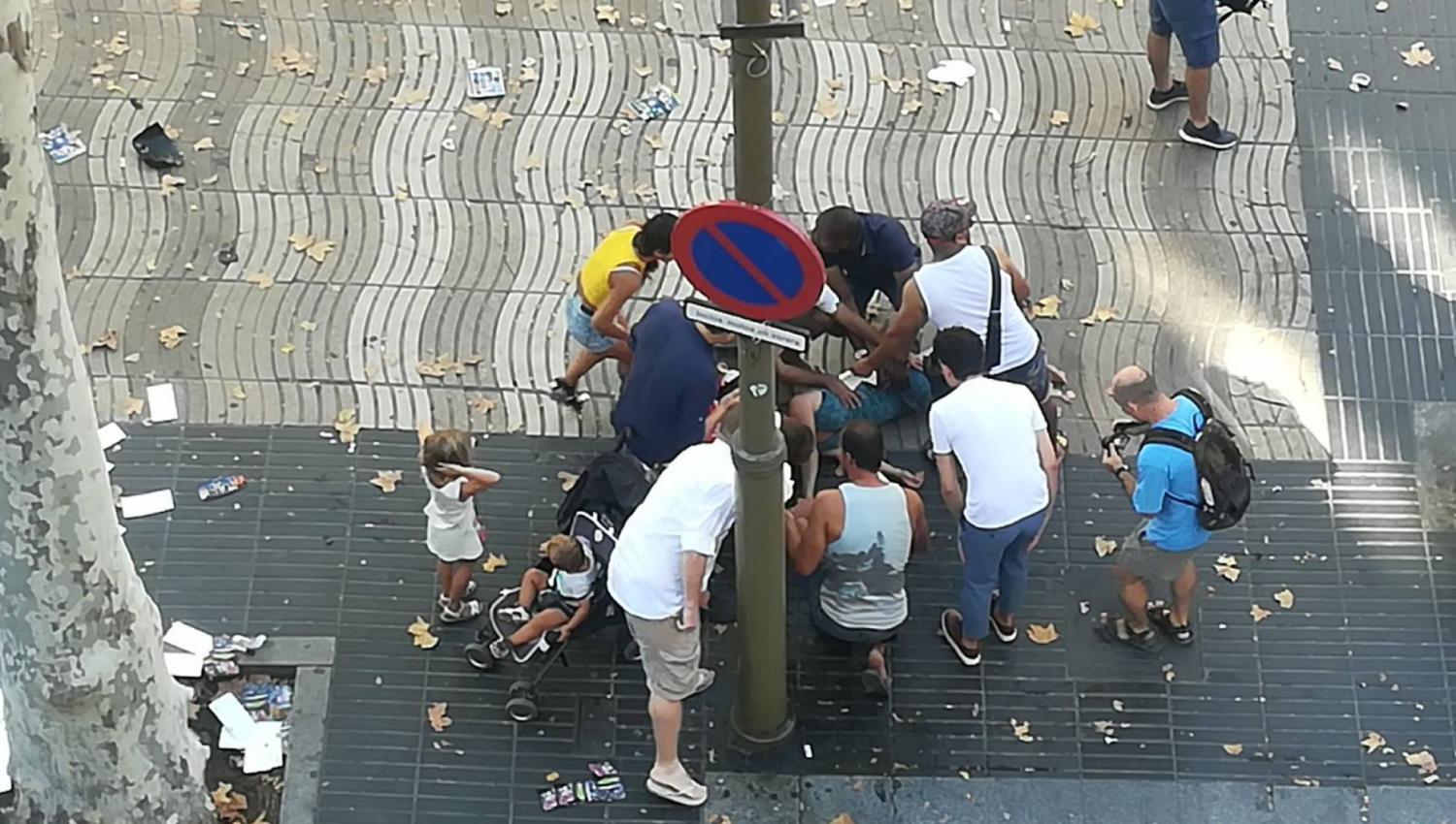 ATENTADO TERRORISTA. Un grupo de personas intenta ayudar a un herido, en Barcelona. 