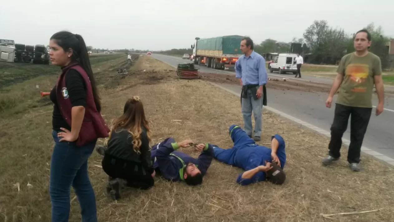LESIONES LEVES. Dos de los ocupantes del camión volcado esperan los primeros auxilios. FOTO ENVIADA POR UN LECTOR