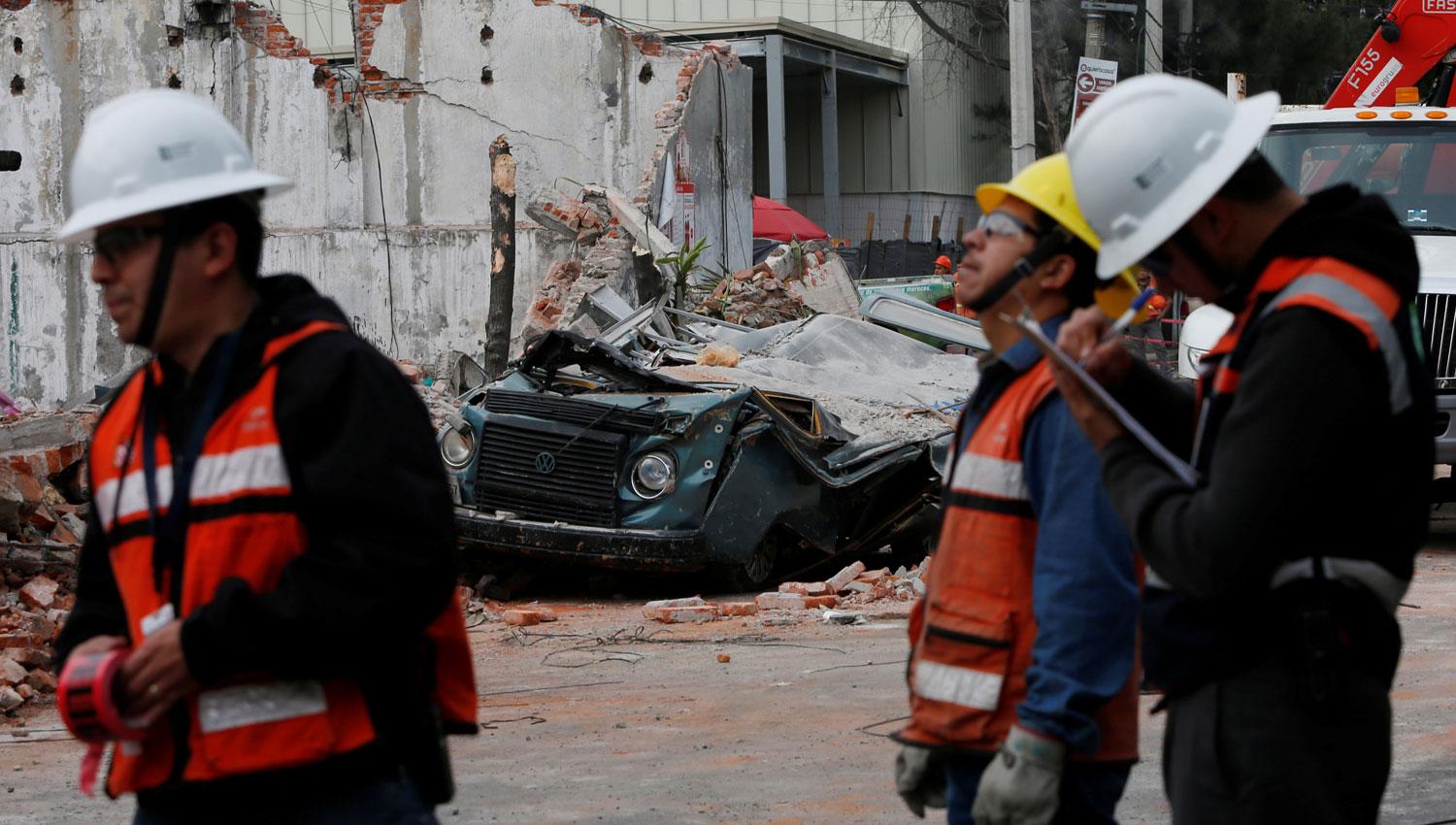 MÉXICO. Rescatistas trabajan cerca de un auto que fue aplastado por los escombros. REUTERS