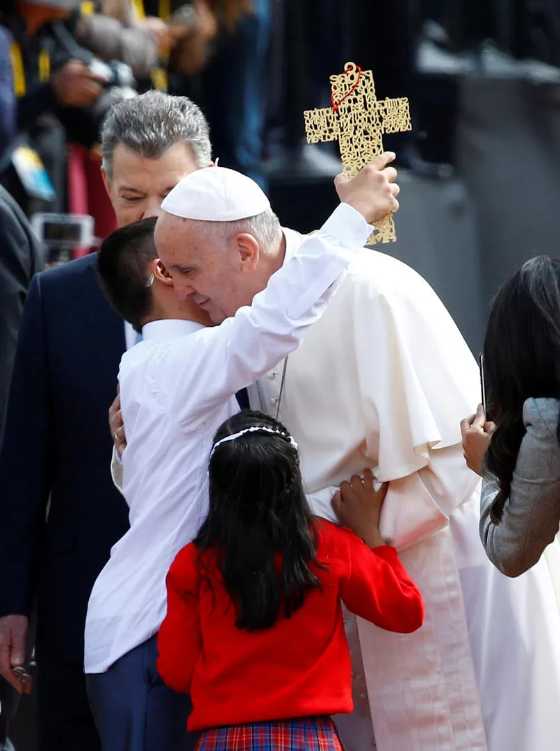 SALUDOS. El Papa abraza a un pequeño; detrás, semitapado, Santos. reuters