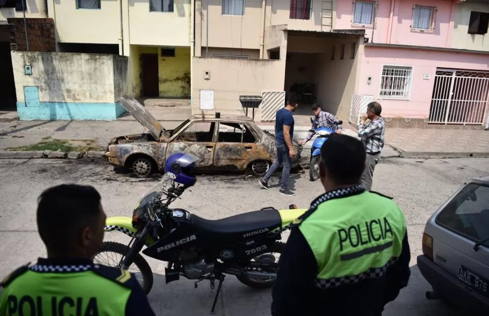 SORPRENDIDOS. Policías y vecinos observan cómo quedó el Renault 18 quemado en la calle Dall Asta al 2.000, frente a la casa de su propietaria.  la gaceta / foto de Osvaldo Ripoll