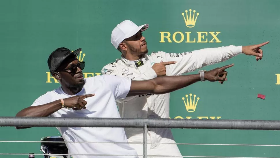 DOS ESTRELLAS. El atleta Usain Bolt subió al podio para festejar el triunfo del británico Lewis Hamilton. De paso, ensayaron el típico festejo del jamaiquino. reuters 