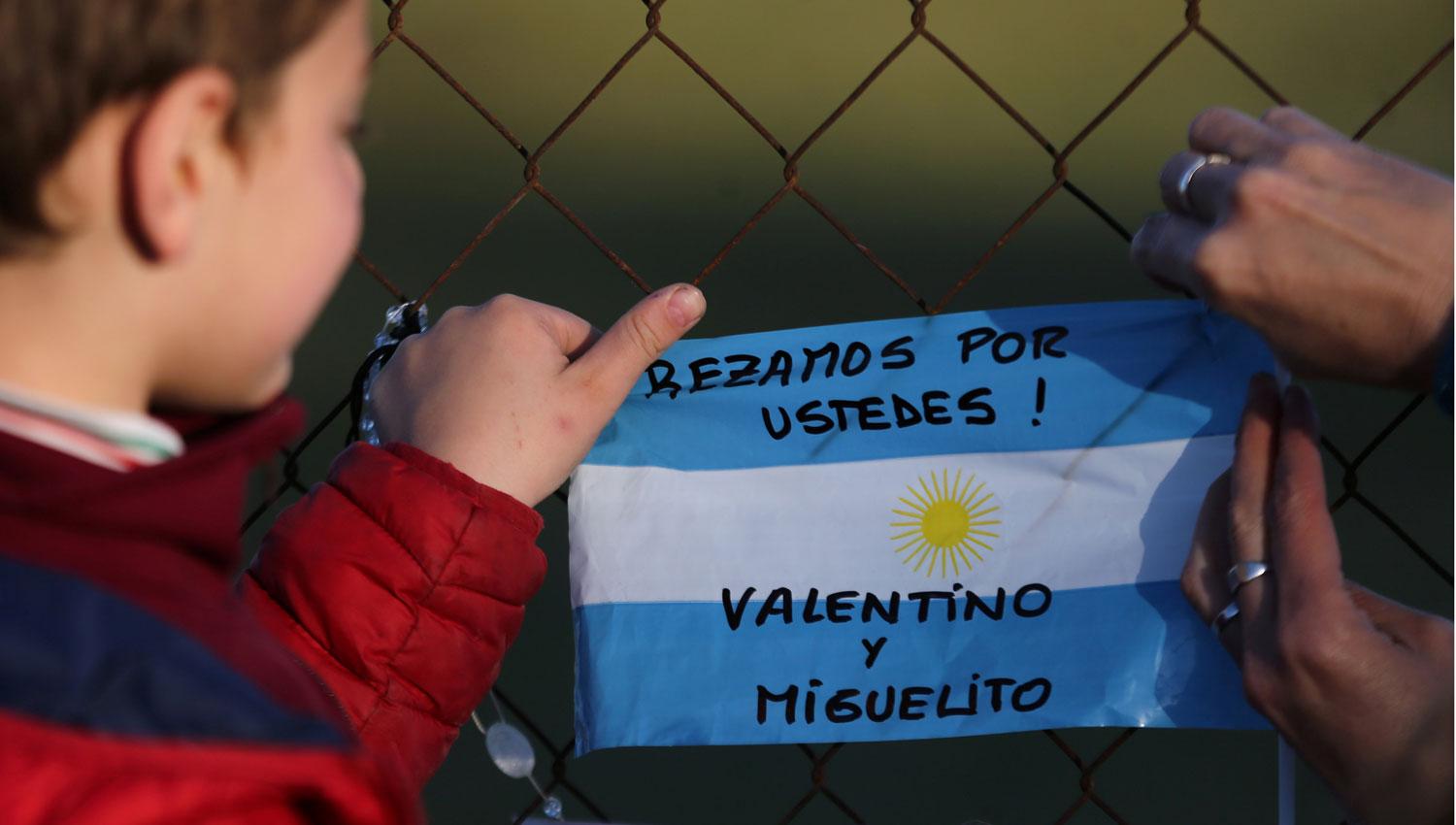 APOYO. Un niño coloca una bandera con mensajes para los tripulantes del San Juan en la base naval de Mar del Plata. REUTERS