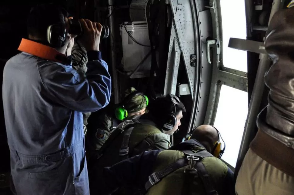 RASTRILLAJE. Miembros de la Armada observan el mar desde uno de los aviones que registran la zona de búsqueda.  reuters