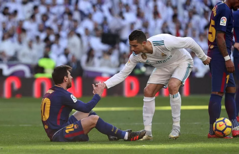 ¿ENEMIGOS? Ronaldo le extiende la mano a Messi que aparece en el suelo. El rosarino volvió a brillar en el clásico español.  