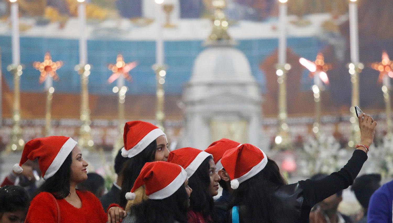 UNA SELFIE. Con el celular en la mano, una joven retrata a sus amigas durante la celebración de la Navidad en Nueva Delhi, en India. REUTERS