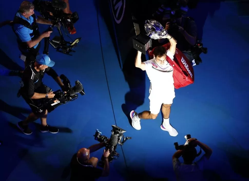 TODOS LOS ÁNGULOS. Federer se retira del estadio Rod Laver con el trofeo. Desde arriba, también se captó su felicidad. reuters