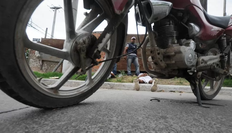 LUEGO DEL ATRACO. Un arrebatador permanece esposado al lado de una moto, en la zona sur de la Capital. la gaceta / foto de OSVALDO RIPOLL