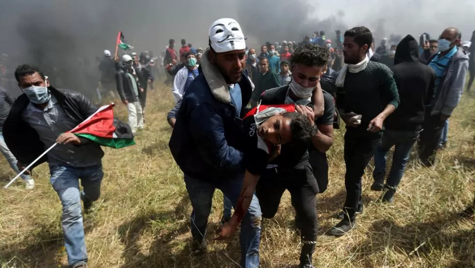 TENSIÓN. Un manifestante palestino herido es evacuado durante enfrentamientos con tropas israelíes. Reuters
