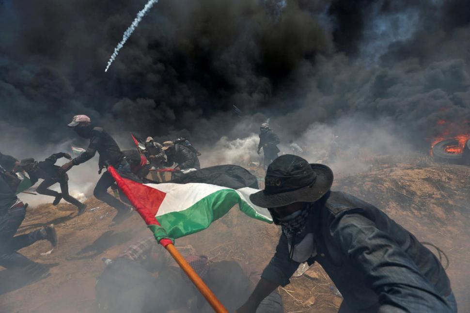 FRONTERA. Jóvenes palestinos corren para ponerse a cubierto de los gases lacrimógenos que lanza el ejército israelí. reuters