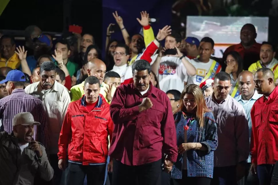 CONTRASTE. Nicolás Maduro, tomando de la mano a su esposa, Cilia Flores, festeja los resultados en la noche del domingo. El abstencionismo fue histórico. Reuters