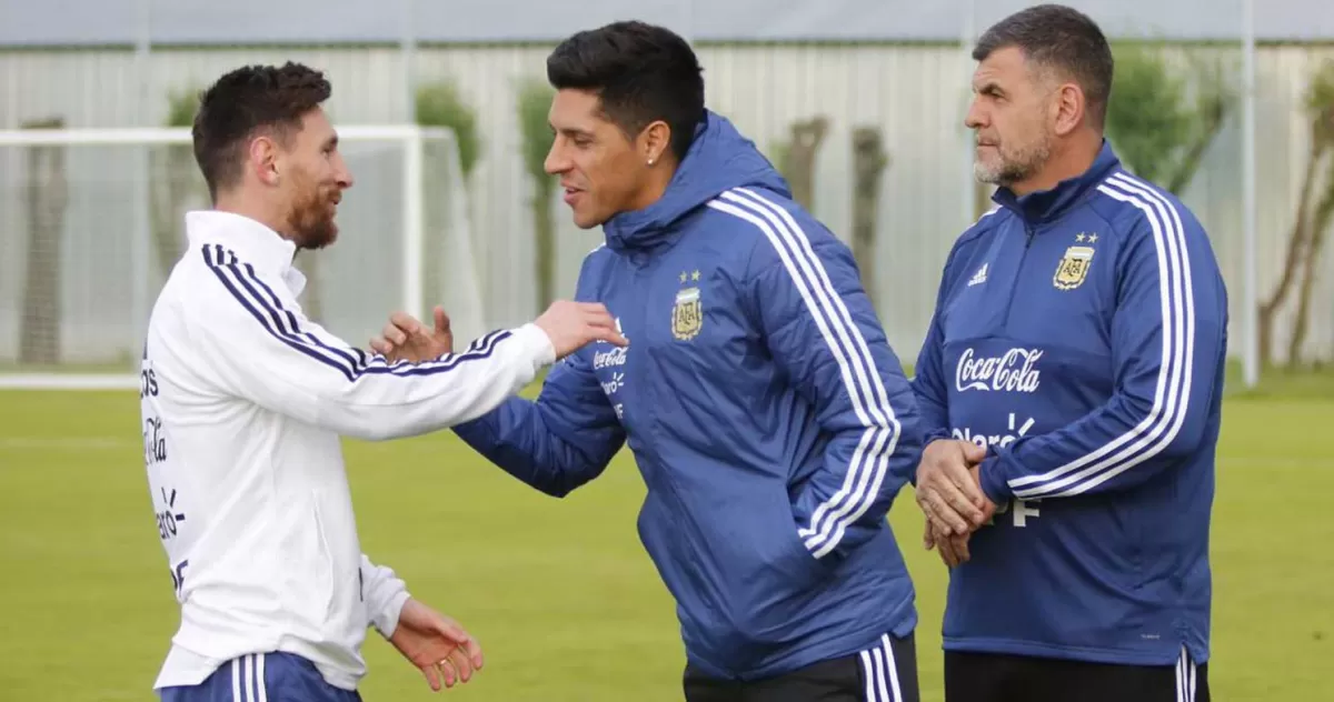 REENCUENTRO. Lionel Messi saluda a Enzo Pérez ante la mirada del masajista Marcelo D’Andrea. El volante llegó con la práctica empezada y se abrazó con todos. (prensa AFA)