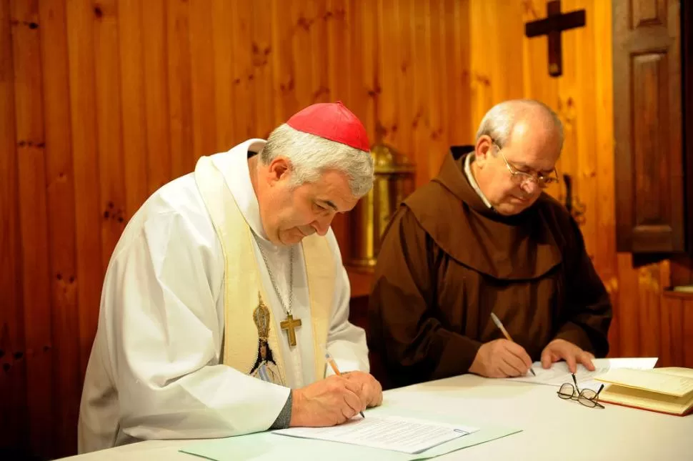 CEREMONIA. El arzobispo Carlos Sánchez y el padre Mateo Kruspsky OFM firman la carpeta que irá a Roma. LA GACETA / FOTO DE HÉCTOR PERALTA.