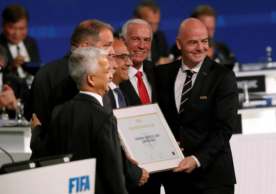 FINAL FELIZ. Infantino (derecha), presidente de FIFA, le entrega la placa a los representantes del triplete que ganó la votación.  reuters