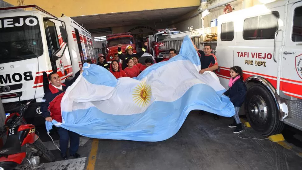 A MODO DE RITUAL. Los bomberos y los cadetes que se están formando desplegaron una gran bandera argentina antes de que comience el partido definitorio, que llevó a la selección argentina a octavos de final. LA GACETA/FOTOS DE OSVALDO RIPOLL