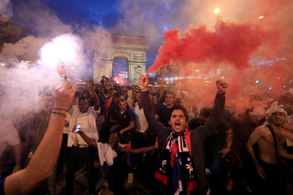PURA FELICIDAD. Los hinchas de Francia festejan en los Campos Elíseos la victoria conseguida por su seleccionado frente a Bélgica y el pase a la gran final. Reuters