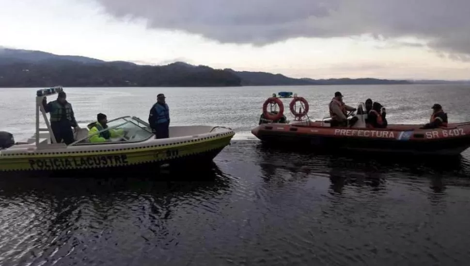 DURO TRABAJO. Los hombres de la Policía Lacustre buscan con ganchos la embarcación de los Jiménez.  