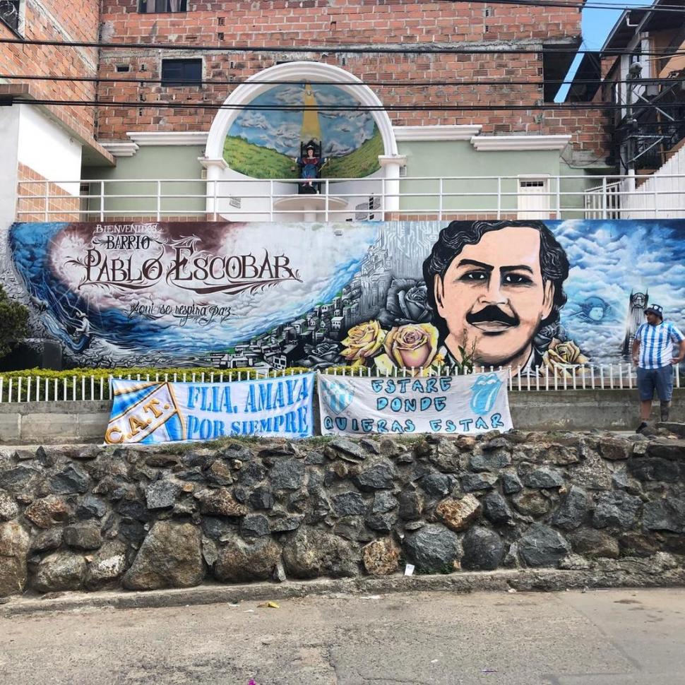 MEDELLÍN. Carlos, miembro de la Comisión del hincha, puso sus banderas junto al mural de Pablo Escobar en Colombia.  