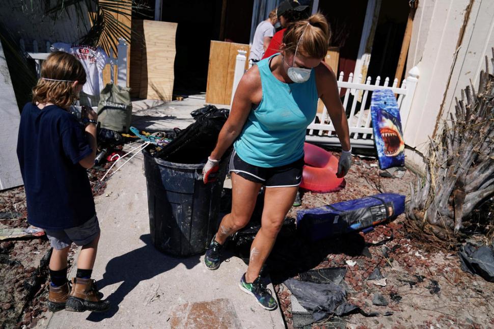 DÍA DESPUÉS. Una familia limpia su casa para volver a dormir en su barrio. fotos Reuters