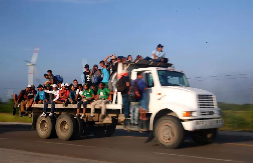 A DEDO. Jóvenes esperan en la ruta de Juchitán a que alguien los lleve.  reuters 