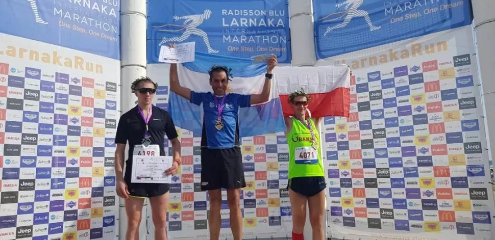 ALTA EN EL CIELO. El tucumano Lencina muestra la bandera argentina en lo más alto del podio de la Maratón de Chipre.  