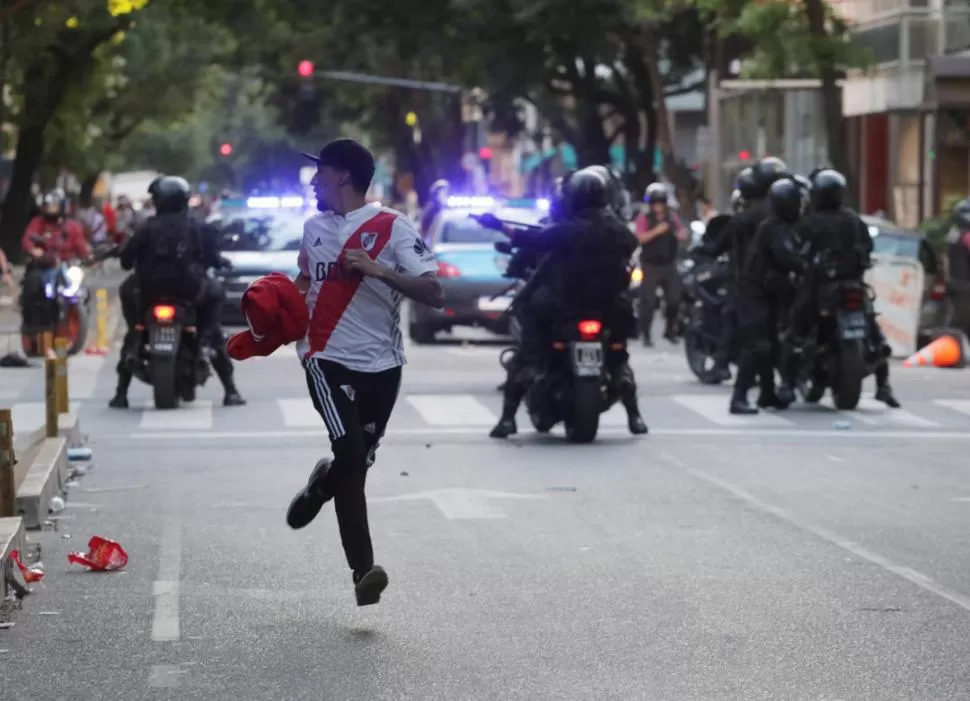 CORRIDA. Un hincha de River huye ante la arremetida de la Policía que finalmente accionó contra algunos de los violentos que generaron los desmanes en las afueras del estadio Monumental.  Reuters
