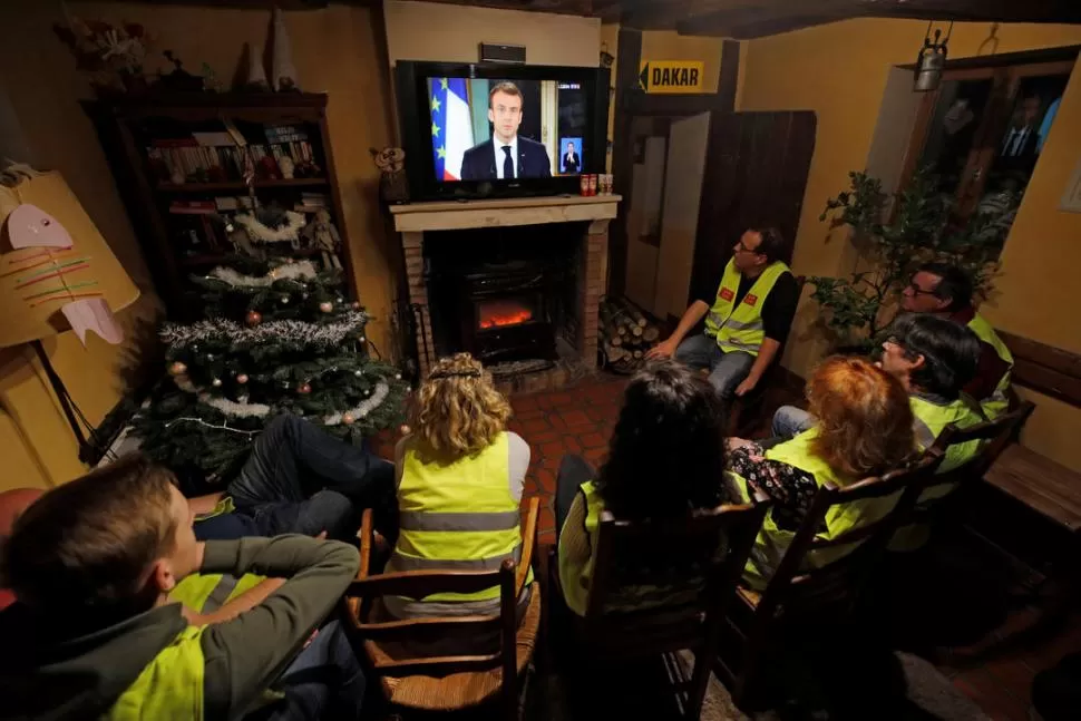 ESPERA. Los manifestantes se reunieron para escuchar el discurso de Macron en casas, cafés y lugares públicos.   reuters 