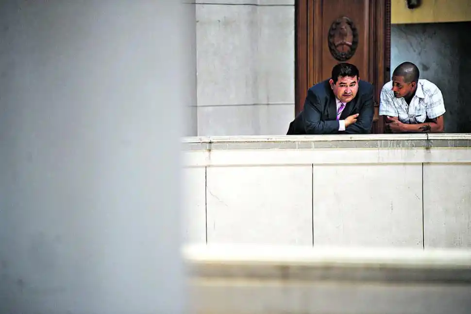 EN EL DESCANSO. El acusado Gómez (de blanco) dialoga afuera de la sala de juicio con uno de sus abogados.