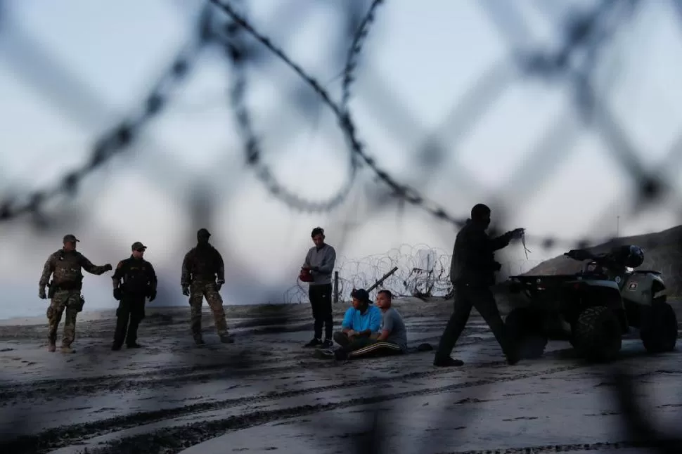 DETENIDOS. Un grupo que intentó cruzar hacia el norte de Tijuana quedó en manos de la policía fronteriza.  reuters 
