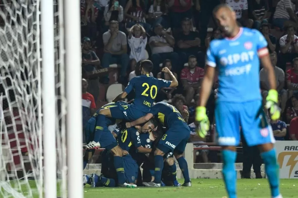 TODOS FELICES. Fernández sufre, mientras atrás de él una “montaña” de jugadores de Boca festeja unos de los tantos. twitter @BocaJrsOficial 