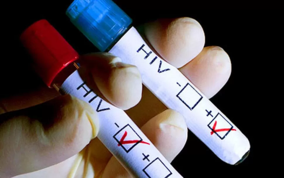 ESTUDIOS. Un especialista manipula tubos con sangre de dos personas: una convive con el virus y la otra, no.  