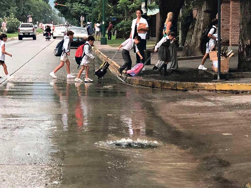 - 5  Estudiantes del colegio San Patricio, en Yerba Buena, cruzan la calle junto a una pérdida de agua clocacal (marzo de 2018).-