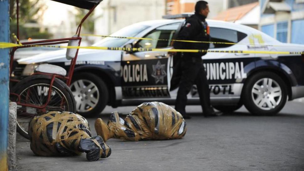 CRÍMENES NARCOS. Un oficial de policía custodia el área donde aparecieron los cadáveres de dos personas asesinadas en Nezahualcoyotl, México. REUTERS
