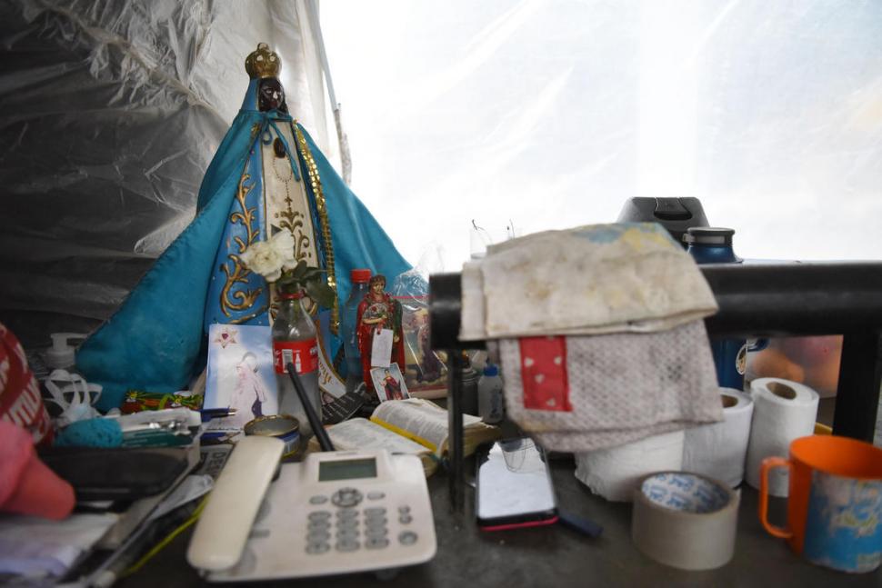 PEQUEÑO ALTAR. Una imagen de la Virgen del Valle, rodeada de estampitas y un teléfono fijo.