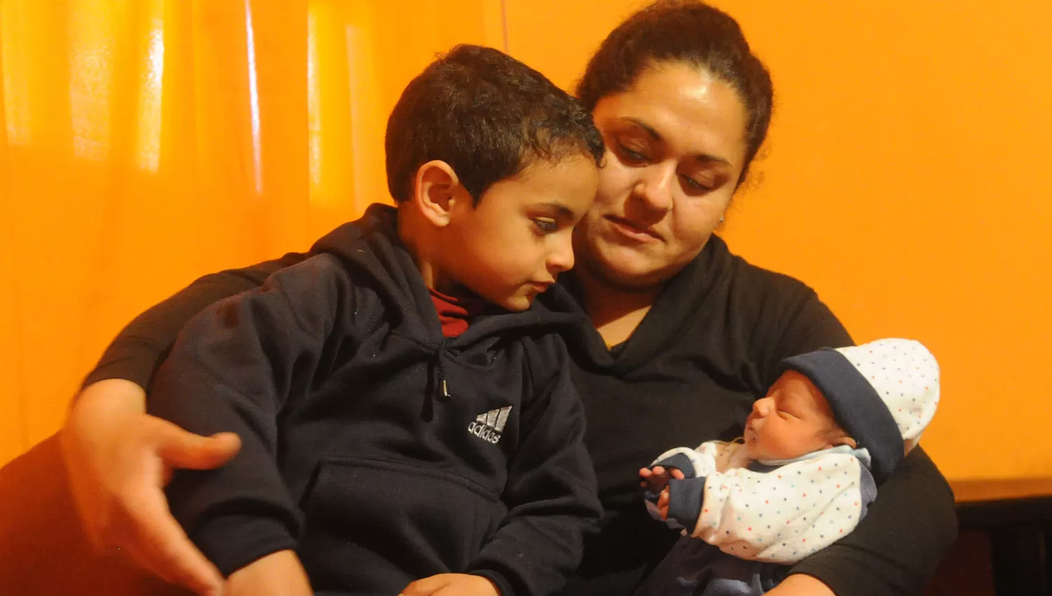MAMA DONANTE. Yanina Serrano posa con sus dos hijos. Ella decidió donar el cordón umbilical de su segundo embarazo. Abajo, un momento de  la cesárea donde se realizó la donación.