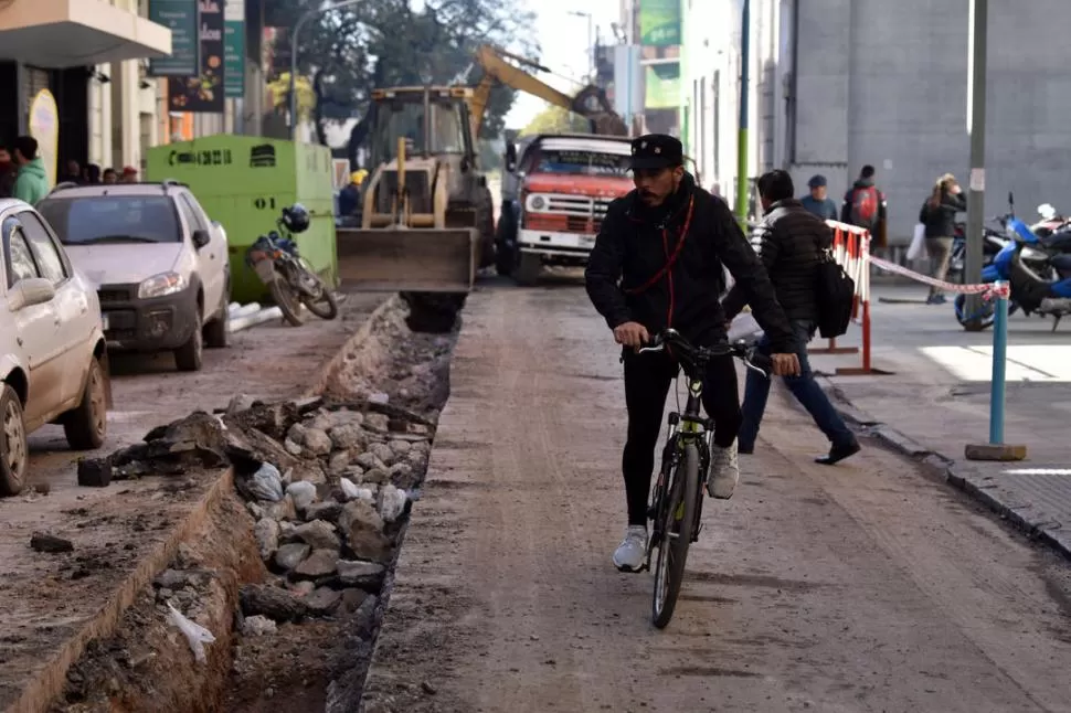 PASO LIMITADO. A pesar del cierre, un ciclista avanza por San Martín al 200, donde el pavimento ya está roto. LA GACETA / FOTOS DE INÉS QUINTEROS ORIO.-