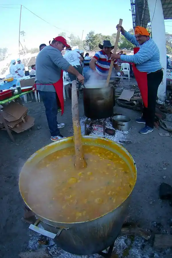 -EN PLENA TAREA. Lo cocineros revuelven el locro en la olla humeante.-