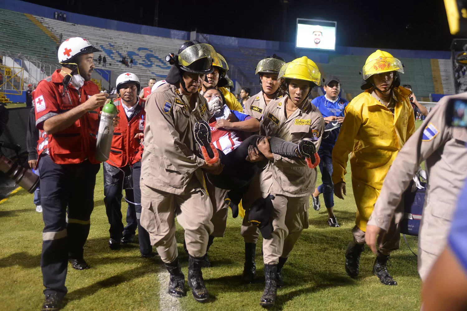 SOCORRO. Bomberos cargan a una mujer que resultó herida en la gresca. REUTERS