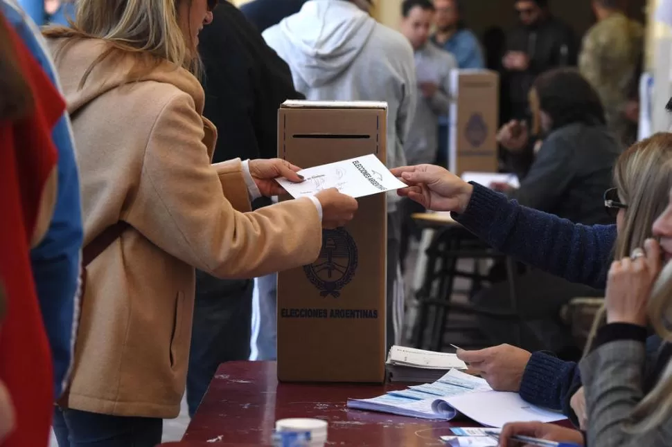 JUNTO A LA URNA. Un presidente de mesa entrega el sobre a una electora. la gaceta / foto de analia jaramillo 