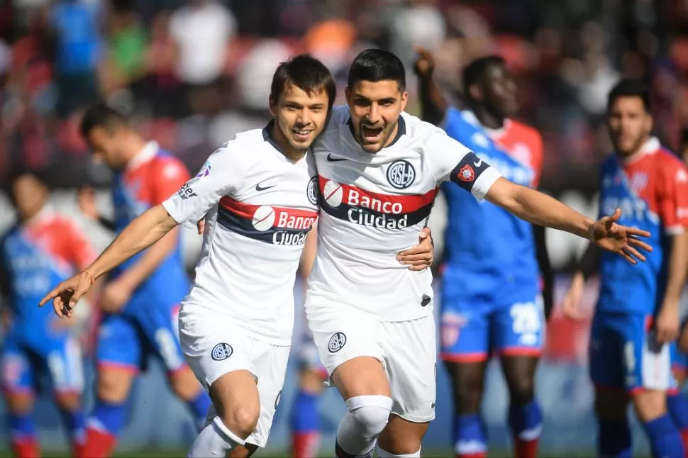 ALEGRÍA. El paraguayo Ángel Romero ya hizo el primer gol del “Ciclón”, y recibe el abrazo del capitán, Nicolás Blandi. telam