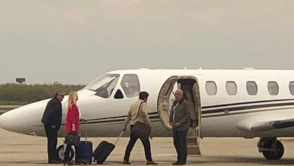 LA IMAGEN QUE CALENTÓ LAS REDES. Magario (de rosa) y Espinoza con valijas, junto al avión oficial de la Provincia.