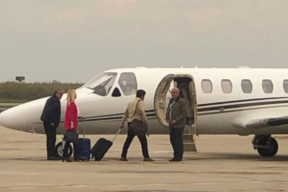 LA IMAGEN QUE CALENTÓ LAS REDES. Magario (de rosa) y Espinoza con valijas, junto al avión oficial de la Provincia.