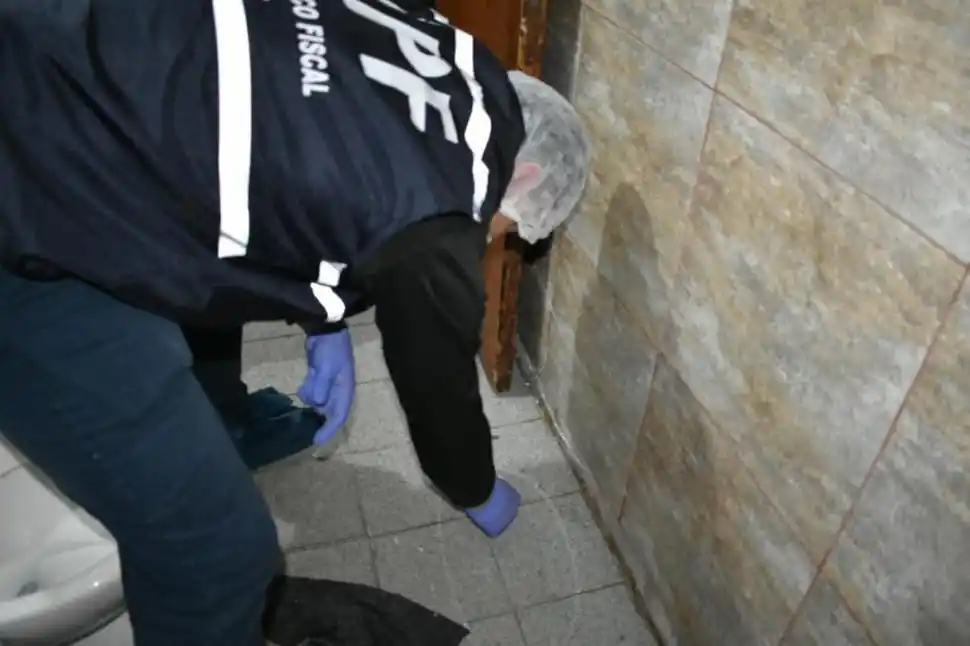 EN PLENA TAREA. Un perito toma una muestra en el baño de la vivienda. 