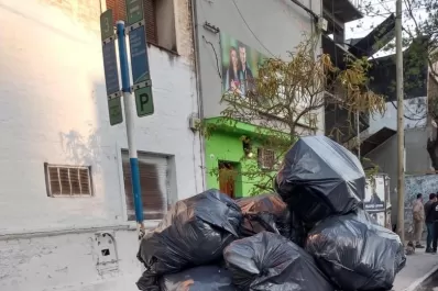 Pasajeros esperan los colectivos entre los olores de un contenedor