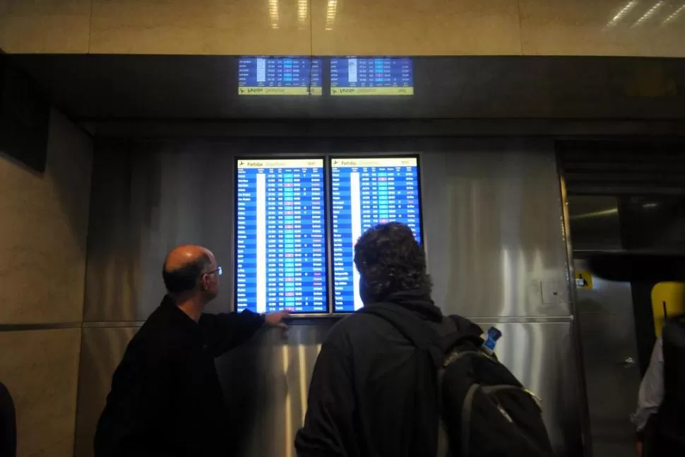 ALIVIO. Dos pasajeros miran una pantalla con la programación de los vuelos. archivo