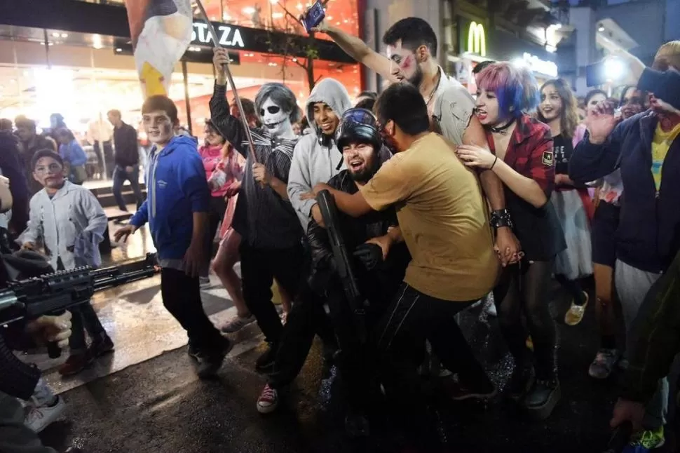 PERFORMANCE. Con rumbo a plaza Independencia, los zombis y los supervivientes recrearon peleas con mordidas y escapatorias por las calles. LA GACETA / FOTOS DE ANALIA JARAMILLO 