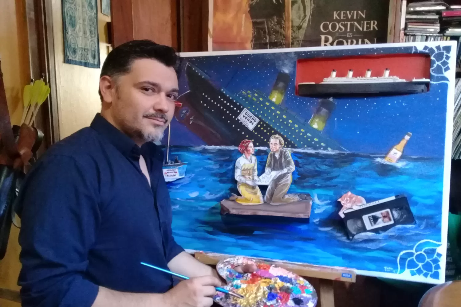 Frido Nuñez, pintando una de las obras que se rifarán en dicienmbre. Tiene inserto un coleccionable del Titanic.